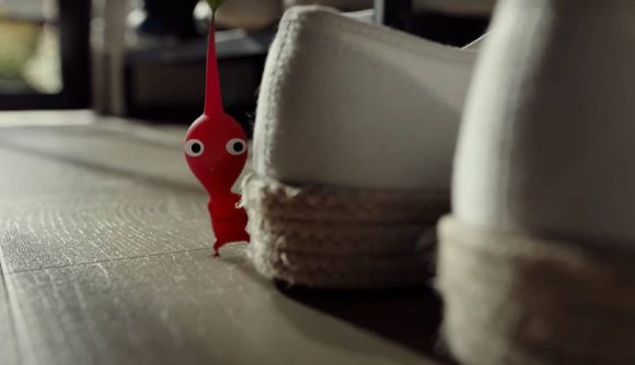 A red Pikmin appears from behind a shoe in a realistic looking world