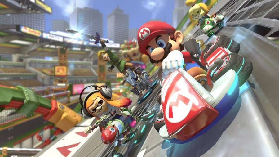 Mario hurtles forwards in a kart, followed closely by an Inkling and Link