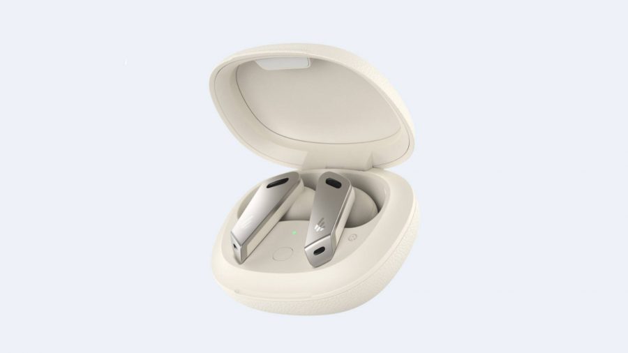 A pair of white and grey wireless earbuds sit in a white charging cradle