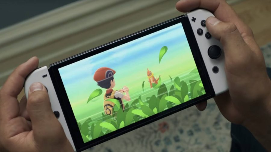 A pair of hands are shown to be playing on the white Nintendo Switch OLED model, with Pokemon Brilliant Diamond or Pokemon Shining Pearl appearing on the vivid screen. 