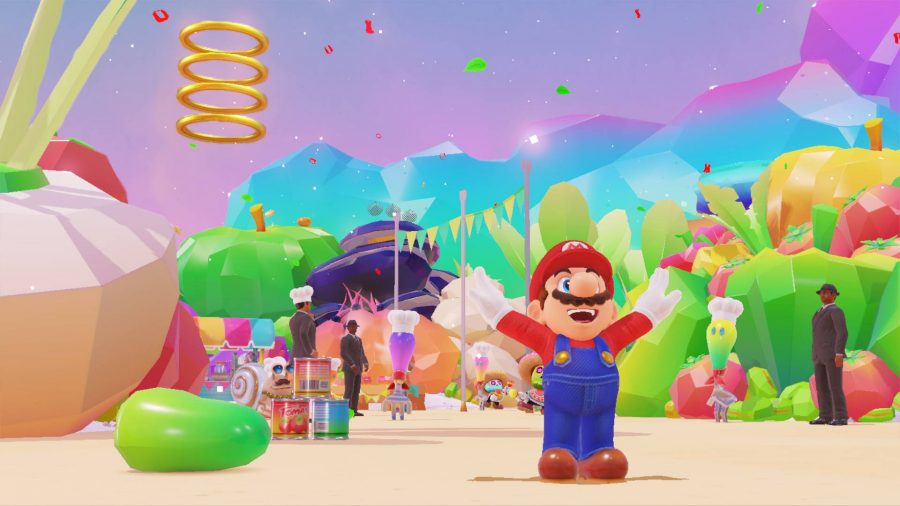 Mario stands with his arms outstretched, while a colourful world full of cutlery wearing chefs hats is visible