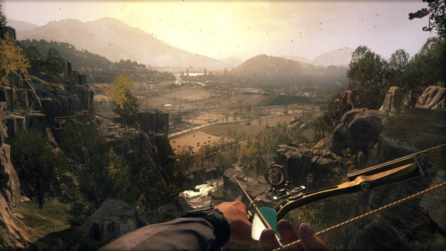 A player holding a crossbow looks out over a large open-world while the sun sets 