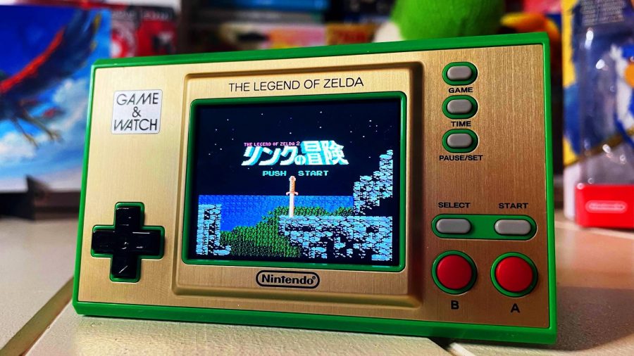 A small, green, Game & Watch shows the time and also has art from The Legend Of Zelda for NES