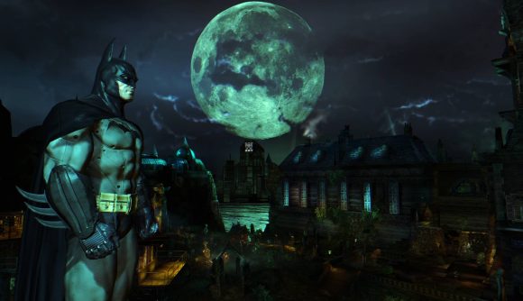 Batman stands tall in the night, with a bright moon behind him
