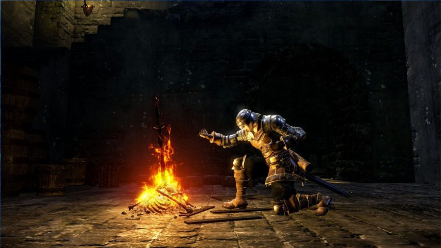 A screenshot from one of the best games like Zelda, Dark Souls, showing the player-character kneeling by a bonfire, arm outstretched.