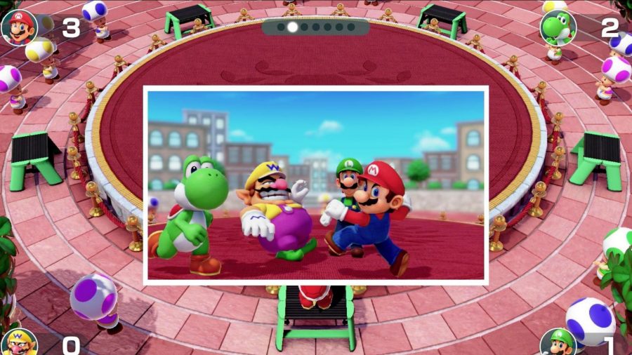 A screenshot from Super Mario party, showing Yoshi, Luigi, Wario, and Mario all fighting to get into a photo frame.