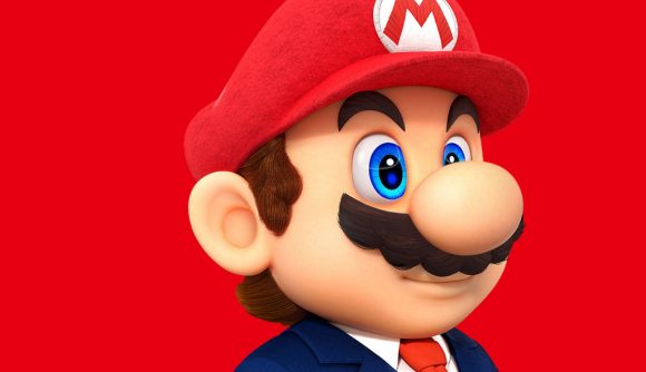 A picture of Mario (a cartoon man with a large round nose, brown hair, and bushy moustache) in a suit, with a red cap on with an M in the middle, all on a red background