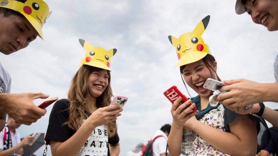 Pokemon Go sixth anniversary interview: a photo shows several people playing Pokemon GO while wearing Pikachu hats 