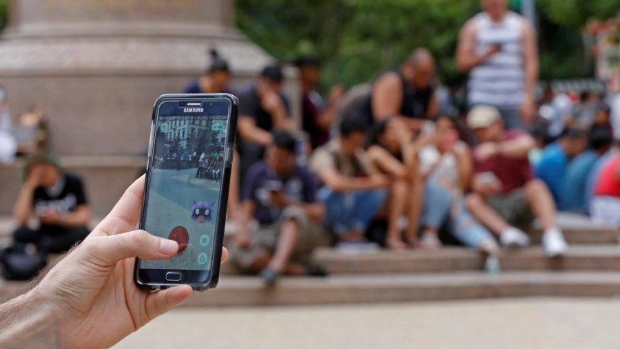 Pokemon Go sixth anniversary Niantic interview: a pokemon go player holds their phone up, showing them attempting to catch a Shellder