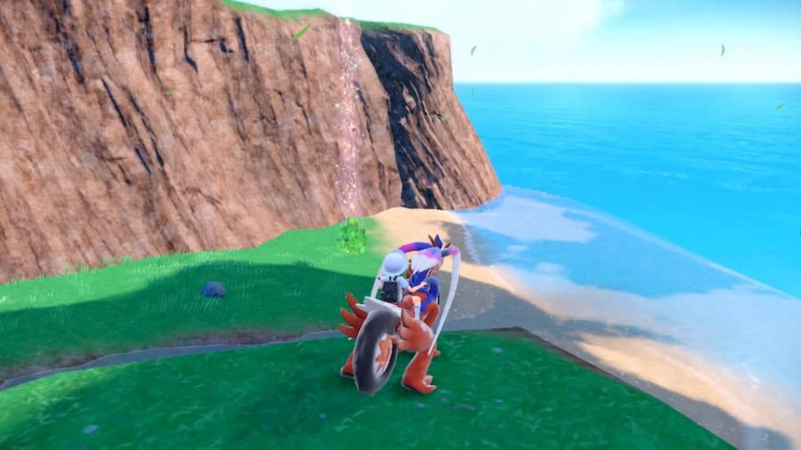 Pokemon Scarlet & Violet Terastal Pokemon: a screenshot shows a Pokemon trainer riding the legendary bike Pokemon Moraidon, while looking out over a valley. A sparkling energy appears in the distance, rising up and out of the ground