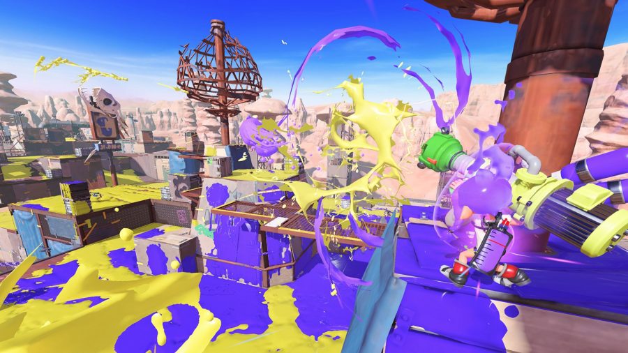 Inkling strzela bronią na arenę na zrzucie ekranu z gry Splatoon 3. Wszystko na arenie jest jak plac zabaw, a kolory farb są losowo fioletowy i żółty.
